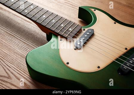 Grüne elektrische Gitarre auf hölzernem Hintergrund, Nahaufnahme. Musikinstrument Stockfoto