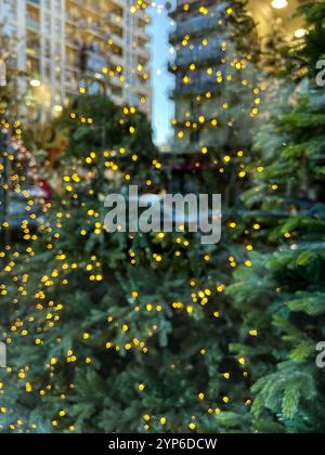 Dieses verwischte vertikale Foto kombiniert die festliche Wärme der goldenen Lichter eines Weihnachtsbaums mit dem modernen Ambiente eines Trubels Stockfoto