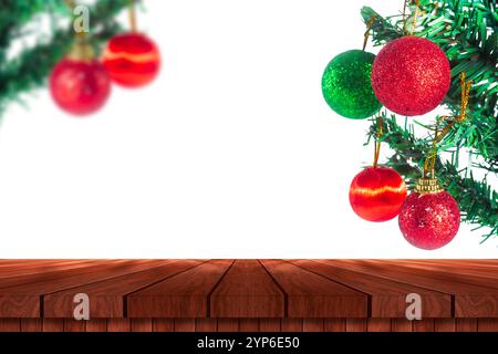 Ein wunderschön dekorierter Weihnachtsbaum mit bunten Ornamenten, vor einem hellen weißen Hintergrund. Ein leerer Holztisch im Vordergrund ist vorhanden Stockfoto