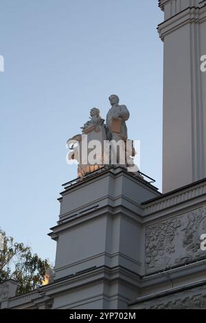 Wunderschöne Statuen zieren elegant die beeindruckend beeindruckende Fassade unter einem klaren, hellblauen Himmel Stockfoto
