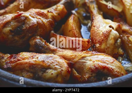 Gebratene Hähnchenkeulen mit Kartoffelscheiben, in einer Tonpfanne, gebacken im Ofen, mit Gewürzen, hausgemacht, keine Leute Stockfoto