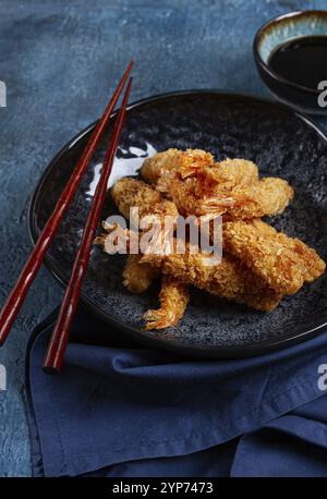 Garnelen in Tempura, frittiert, auf einem schwarzen Teller, mit Sojasauce, Nahaufnahme, Blick von oben, keine Leute Stockfoto