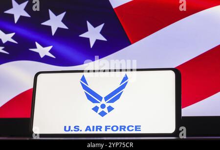 In dieser Fotoabbildung wird das Logo der United States Air Force (USAF) auf einem Smartphone-Bildschirm angezeigt, die Flagge der Vereinigten Staaten im Hintergrund Stockfoto