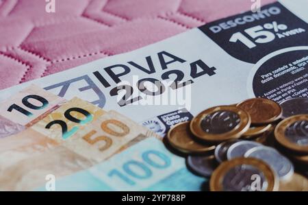 In dieser Fotoabbildung befindet sich der Zahlungsbeleg IPVA (Imposto sobre a Propriedade de Veiculos Automotores) neben brasilianischen Echtgeld-Banknoten und -Münzen Stockfoto