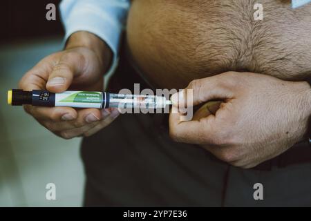 Auf diesem Foto spritzt ein Mann menschliches Insulin in den Körper zur Blutzuckerkontrolle Stockfoto