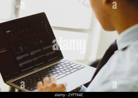 Auf diesem Foto surft ein Mann über ein Apple MacBook im Internet und recherchiert den Aktienkurs an der Börse Stockfoto