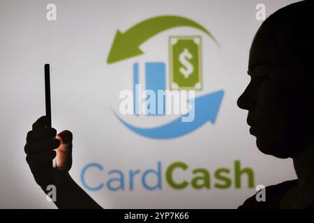 In dieser Fotoabbildung hält die Silhouette einer Frau ein Smartphone mit dem CardCash-Logo im Hintergrund Stockfoto