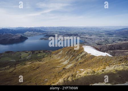 Landschaft mit einem weiten Blick auf einen See, ein Tal und eine ferne Stadt, Roys Peak, Wanaka, Neuseeland, Ozeanien Stockfoto