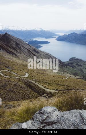 Gewundener Bergweg mit Blick auf einen See in der Ferne, Roys Peak, Wanaka, Neuseeland, Ozeanien Stockfoto