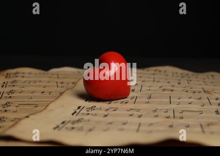 Herzfigur und Musiknoten auf schwarzem Hintergrund, Nahaufnahme Stockfoto