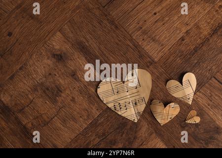 Papierherzen mit Notizen auf Holztisch, flach gelegt. Leerzeichen für Text Stockfoto