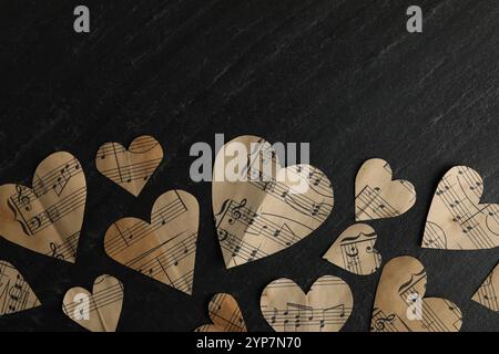 Papierherzen mit Notizen auf schwarzem Tisch, flache Lagen. Leerzeichen für Text Stockfoto