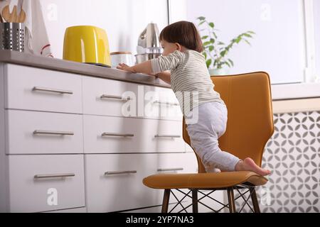 Kleiner Junge, der mit Toaster in der Küche spielt. Gefährliche Situation Stockfoto