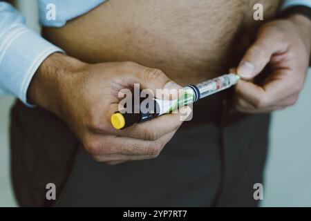 Auf diesem Foto spritzt ein Mann menschliches Insulin in den Körper zur Blutzuckerkontrolle Stockfoto