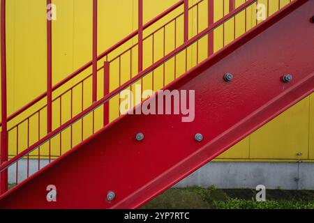 Rote Fluchttreppe außerhalb der Treppe an einem Industriegebäude mit gelber Wand Stockfoto