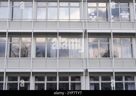 Ein modernes Gebäude mit symmetrischen Glasfenstern, die Himmel und Bäume reflektieren Stockfoto