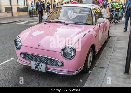 London, Großbritannien, 19. September 2024: Rosa Retro-Auto Nissan Figaro parkt auf der Straße. Stockfoto