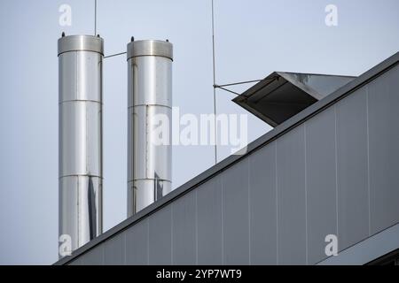 Große Edelstahlschornsteine auf dem Dach eines Industriegebäudes Stockfoto