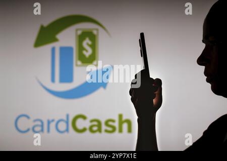 In dieser Fotoabbildung hält die Silhouette einer Frau ein Smartphone mit dem CardCash-Logo im Hintergrund Stockfoto