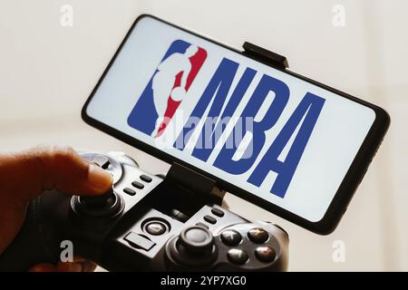 In dieser Fotoabbildung spielt eine Person mit einem Joystick und dem Logo der National Basketball Association (NBA), das auf einem Smartphone-Bildschirm angezeigt wird Stockfoto