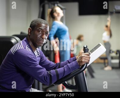 Afrikanischer Mann mit Fahrrad im Fitnessstudio Stockfoto