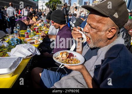 Los Angeles, Usa. November 2024. Die Leute genießen ihre Thanksgiving-Mahlzeit. Tausende von Einwohnern der Skid Row und Obdachlosen aus der Innenstadt und darüber hinaus wurden während des jährlichen Feiertags der Los Angeles Mission Thanksgiving Dinners serviert. Quelle: SOPA Images Limited/Alamy Live News Stockfoto