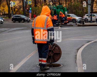 Kanalisationsarbeiter, die den Gullyschacht reinigen und die Kanalisation auf der Straße freimachen. Stockfoto