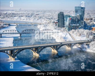 Eine verschneite Stadt mit einer Brücke über einen Fluss. Die Brücke ist mit Schnee bedeckt und die Stadt ist nachts beleuchtet Stockfoto