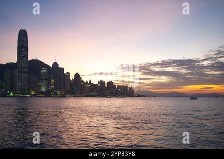 Die Skyline im Zentrum von Hongkong bei Sonnenuntergang mit violettem und orangefarbenem Himmel über dem Victoria Harbour. Hongkong - 25. Oktober 2024 Stockfoto