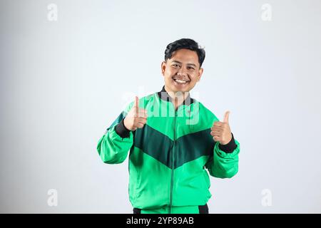 Porträt eines asiatischen Online-Kurierfahrers mit grüner Jacke, mit einem Schild „Good Job“, zwei Daumen hoch Geste Stockfoto