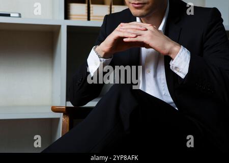 Geschäftsmann sitzt auf einem Stuhl vor dem Bücherregal Stockfoto