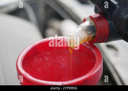 Nahaufnahme des Motoröls, das während der Fahrzeugwartung eingegossen wird Stockfoto