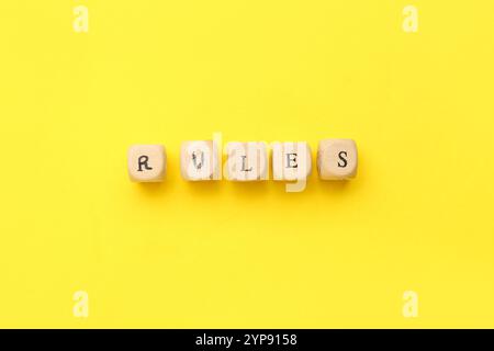 Holzwürfel mit WORTREGELN auf gelbem Hintergrund Stockfoto