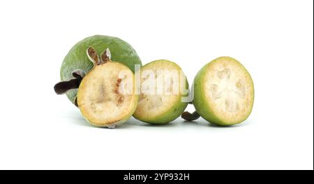 Ein Nahaufnahme-Bild frischer, grüner Feijoa-Früchte, sowohl ganz als auch in Scheiben, die ihre Textur und leuchtende Farbe vor einem sauberen weißen Rücken zeigen Stockfoto