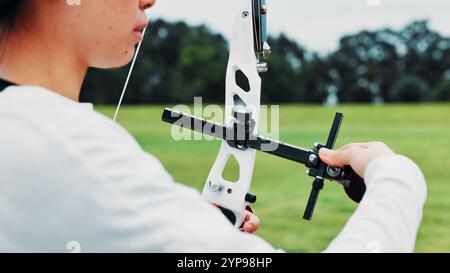 Frau, Bogenschießen und Hände auf dem Feld als Sport für Schießübungen und Sportlertraining in Japan. Nahaufnahme, weibliche Person und Aufbau Rekurvbogen oder Stockfoto