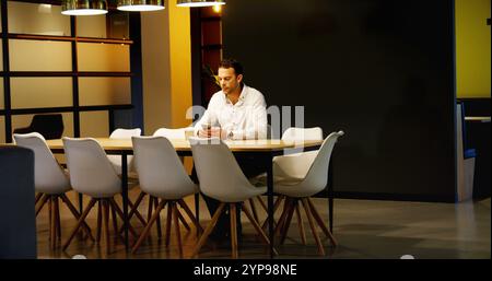 Entfernte Sicht auf gut gekleidete männliche Führungskräfte, die das Handy benutzten, während sie in der Cafeteria einen Kaffee tranken Stockfoto