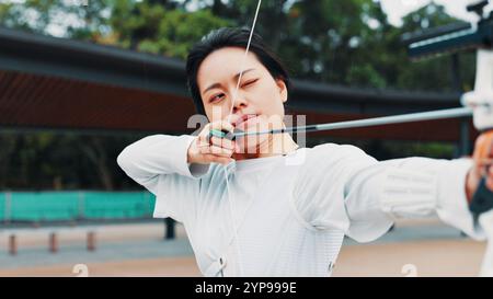 Frau, Ziel und Pfeil für Bogenschießen an der Akademie, Outdoor-Übungen und Bogenpräzision. Weibliche Person, Schießwettbewerb und Park für Wettkämpfe Stockfoto