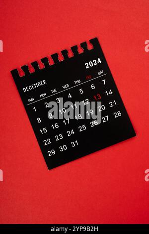 Schwarzer Kalender Dezember 2024 Fokus auf freitag 13, auf rotem Hintergrund. Stockfoto