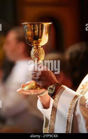 Hand des Priesters mit Kelch in der Kirche Stockfoto