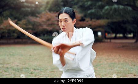 Holzschwert, Japaner und Outdoor im Training, Sport oder Sport als Kampfsportler. Frau, Kultur und Waffe für Herausforderung, Kampf Stockfoto