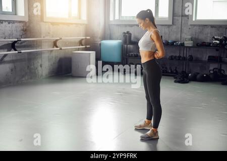 Eine fokussierte junge Frau bereitet sich fleißig auf ein intensives Workout in einem modernen Fitnessstudio vor Stockfoto
