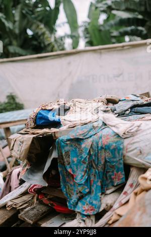 Ein Haufen abgenutzter und unbrauchbarer Kleidung, die in einem Abfalleimer entsorgt wird, symbolisiert Abfall und Umweltprobleme Stockfoto