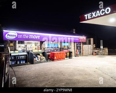 Penny Petroleum Texaco Tankstelle und 24-Stunden-Geschäft glühend im Licht an einem dunklen Winterabend mit Costa Express Schild sichtbar. Stockfoto