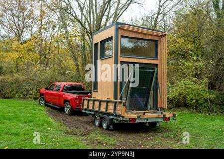 Modernes kleines Haus (Homnest Company) auf Rädern, die von einem roten Lkw gezogen werden, in einer malerischen Herbstlandschaft. Puy de Dome. Auvergne. Frankreich Stockfoto