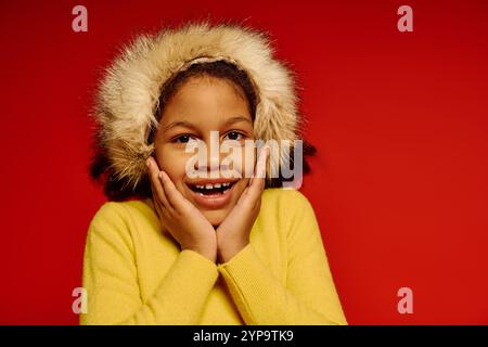 Ein fröhliches kleines Mädchen in Gelb umhüllt die Freude an Weihnachten 2025 mit Freude. Stockfoto