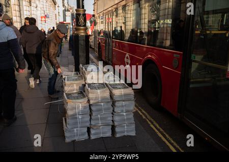 Auf der Straße entlang Piccadilly, im Zentrum von London, England, Großbritannien, stehen Stapel von Abendzeitungen Stockfoto