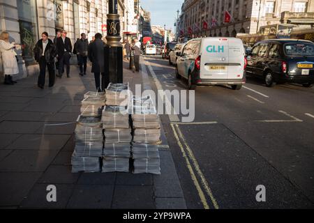 Auf der Straße entlang Piccadilly, im Zentrum von London, England, Großbritannien, stehen Stapel von Abendzeitungen Stockfoto