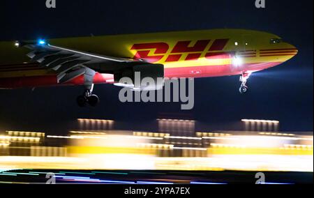 Leipzig, Deutschland. November 2024. Ein DHL-Flugzeug landet am späten Abend am DHL-Drehkreuz am Flughafen Leipzig/Halle. Mit dem Frachtzentrum der Post-Tochter DHL ist der Flughafen eines der weltweit wichtigsten Luftfrachtzentren. Quelle: Hendrik Schmidt/dpa/Alamy Live News Stockfoto