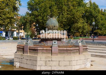 Ein Brunnen mit einer großen Blume oben ist von einer Steinmauer umgeben Stockfoto