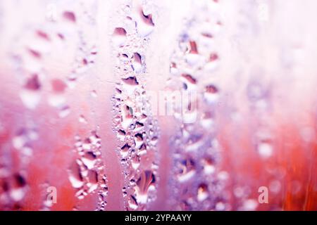Deilcate Regentropfen Wasser auf Glas in einem rosa Glow für Hintergrund Stockfoto